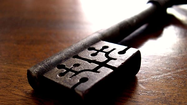 A pen resting on the signature line of a printed agreement, with a small set of car keys placed alongside