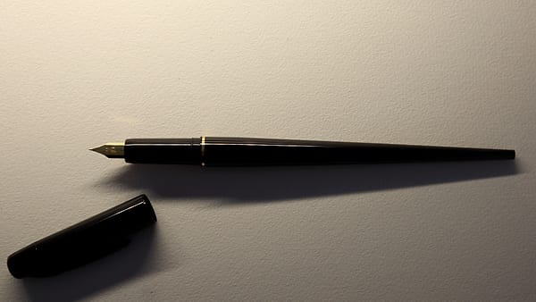 A printed form on a clipboard with handwritten entries in the date and time fields and a pen resting across it