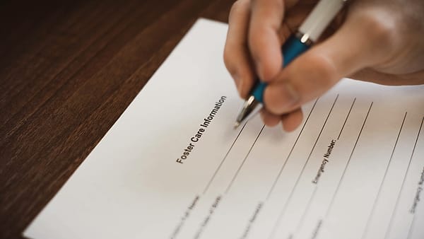 A printed release form on a clipboard with a pen laid across it on a folding table outdoors
