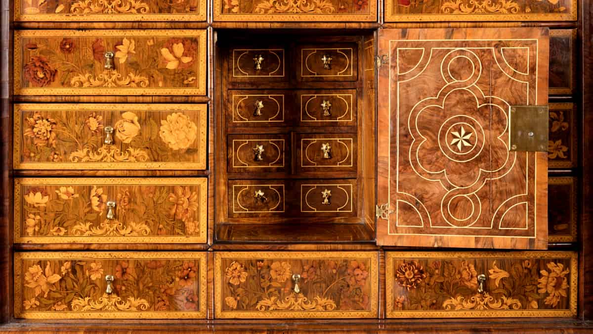 A locked steel cabinet with a heavy hasp and padlock standing against a plain wall in a back room