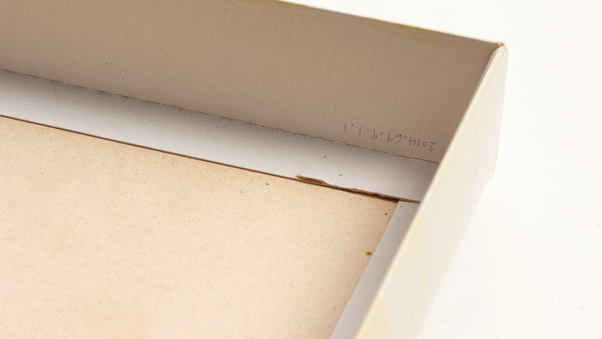 A first aid kit open on a counter with an adhesive bandage wrapper and a paper form beside it