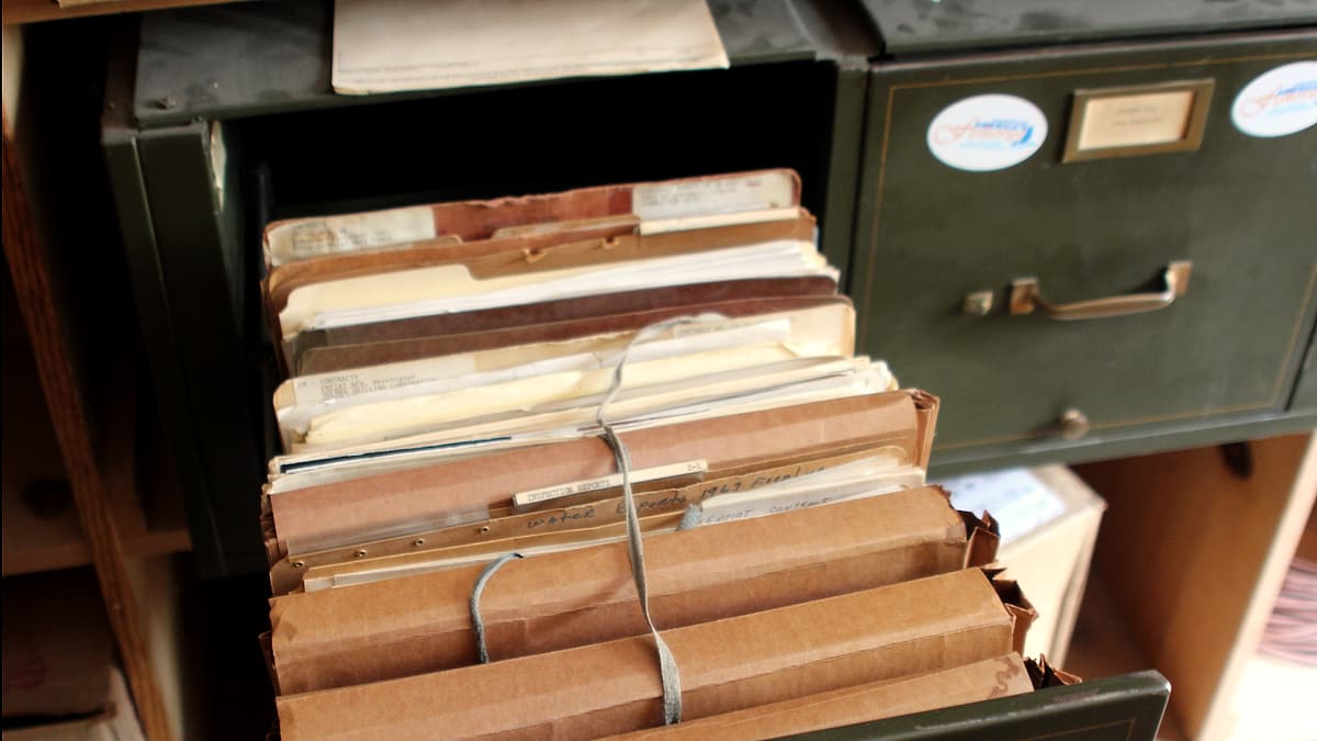 A fingerprint scanner and a clipboard of forms on a plain office desk beside a closed manila folder